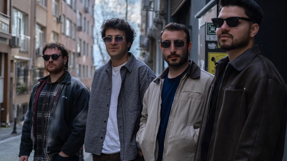 Four men wearing sunglasses pose casually in a narrow street in Istanbul, showcasing a stylish urban vibe.